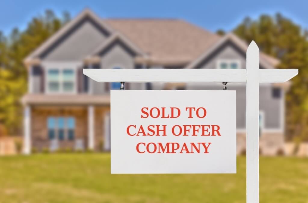 A house with a "Sold To Cash Offer Company" sign displayed prominently in its front yard.