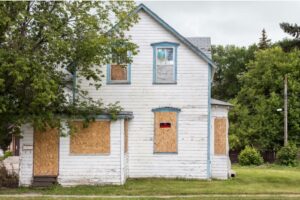 A two-story boarded-up house with a 