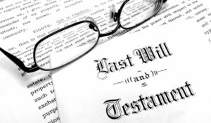 Photo of a Last Will and Testament document on a wooden table with a pen and reading glasses, symbolizing estate planning and probate.